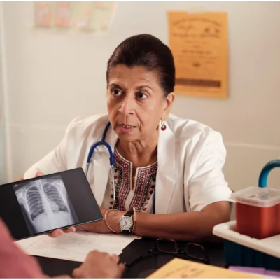 A woman doctor holding a chest x-ray looking at a patient