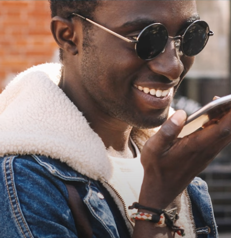 A man in sunglasses speaks into a cell phone