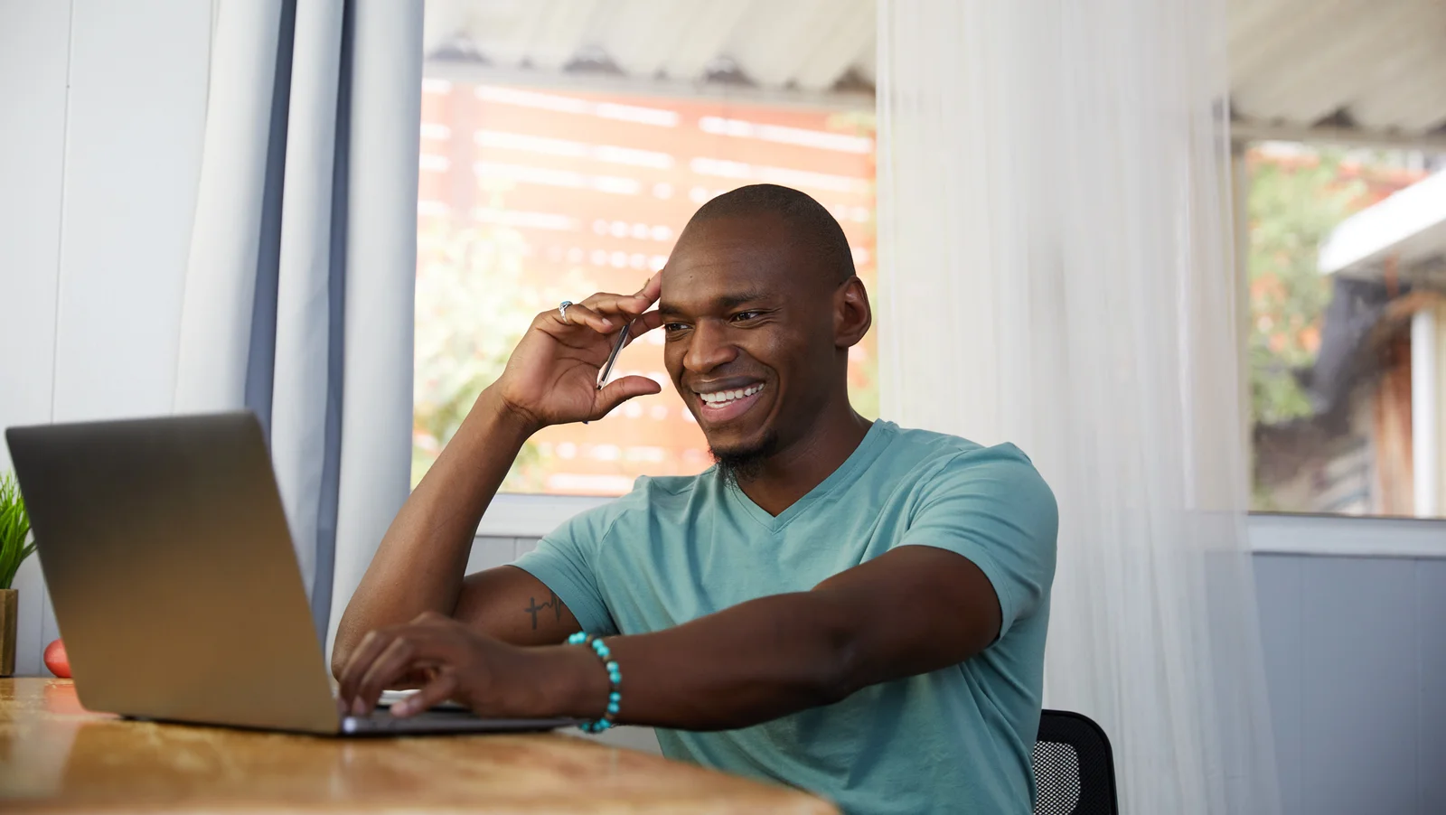 Photo of a man sitting at a desk looking at a laptop screen.