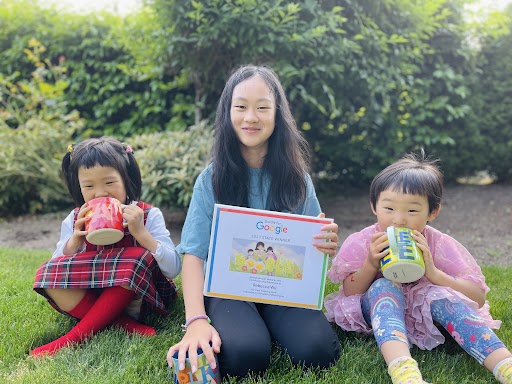 Photograph of Rebecca sitting on grass with her two younger sisters beside her