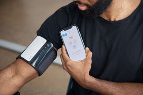 Man using blood pressure monitor to measure blood pressure through his phone