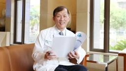 China Medical University Hospital Superintendent Dr Der-Yang Cho sitting on a chair while holding a paper report