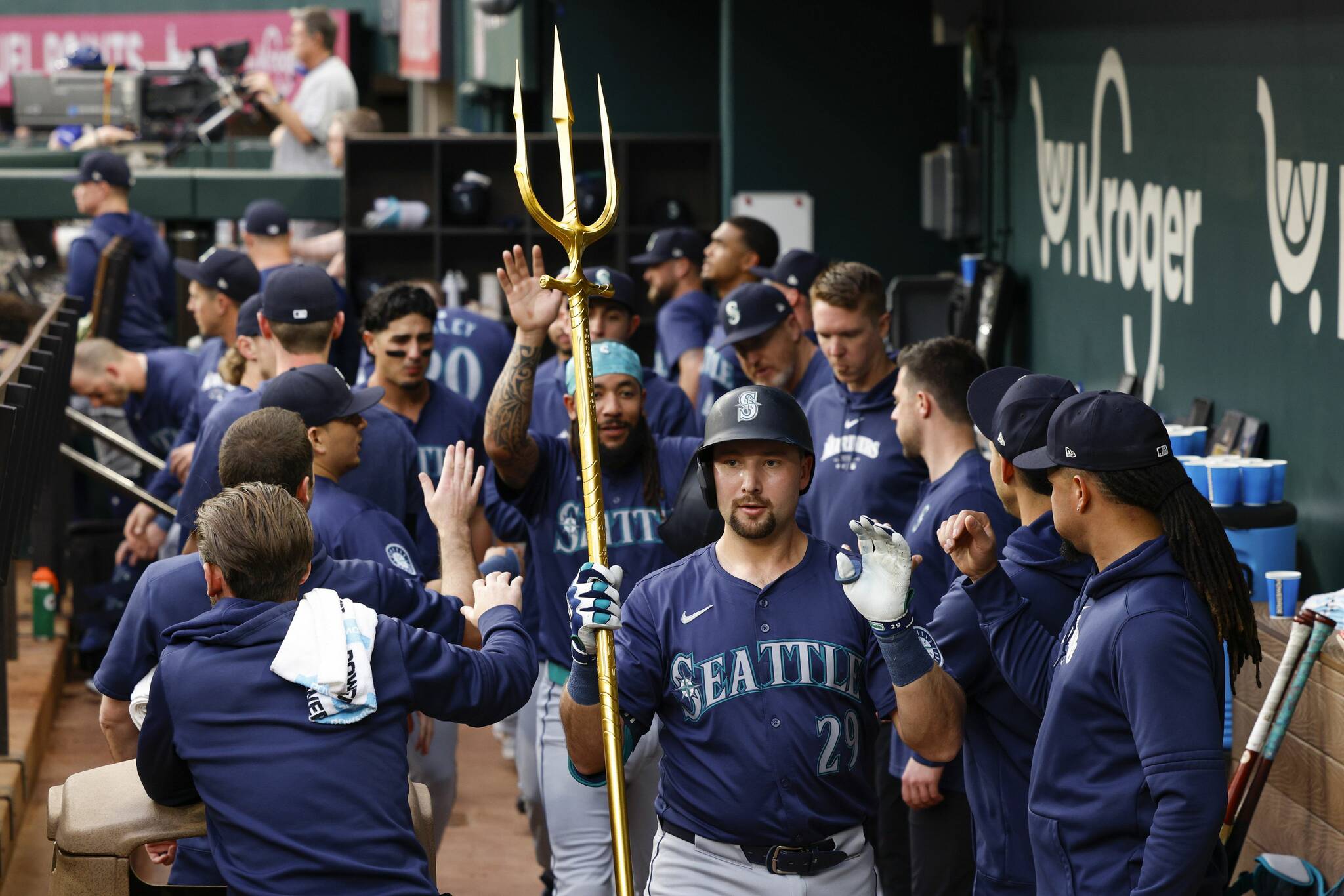 Seattle Mariners catcher Cal Raleigh (29) celebrates his two-run home run with a trident as he high fives teammates during the first inning against the Texas Rangers on Tuesday, April 23, 2024, in Arlington, Texas. (Elías Valverde II / Tribune News Service)