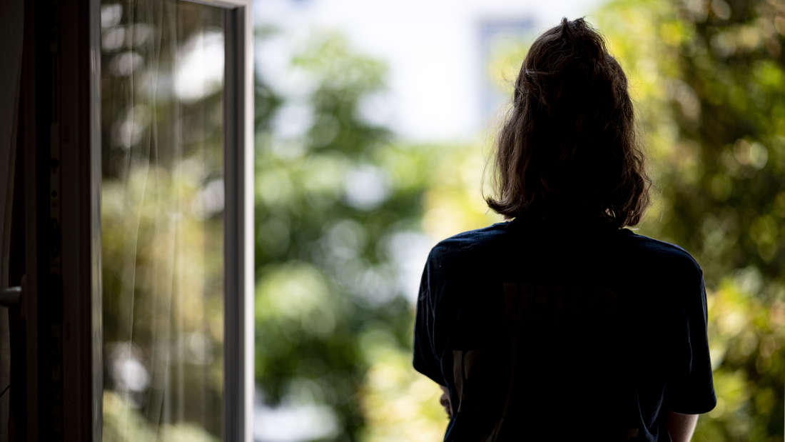 Frau schaut aus Fenster