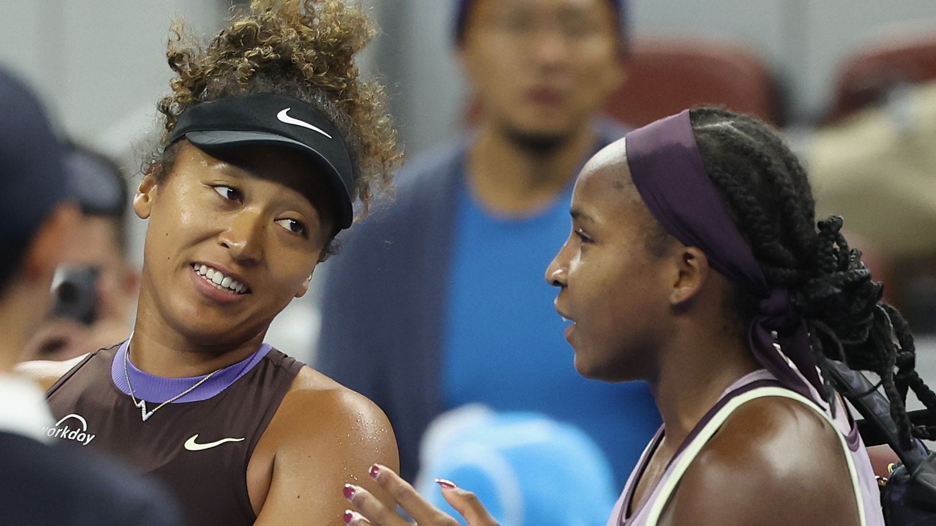 Naomi Osaka is helped off the court by Coco Gauff after forfeiting tennis match