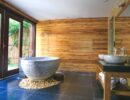 horizontal wood board paneling behind vessel bathtub and sinks