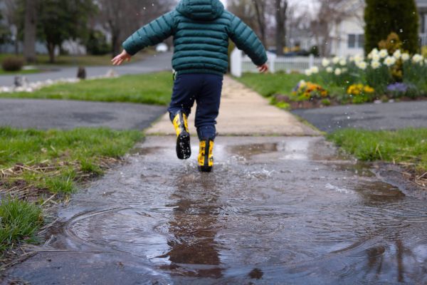 A child running through a puddle from a French drain cleaning.