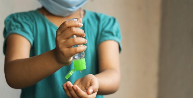 Masked girl using sanitizer