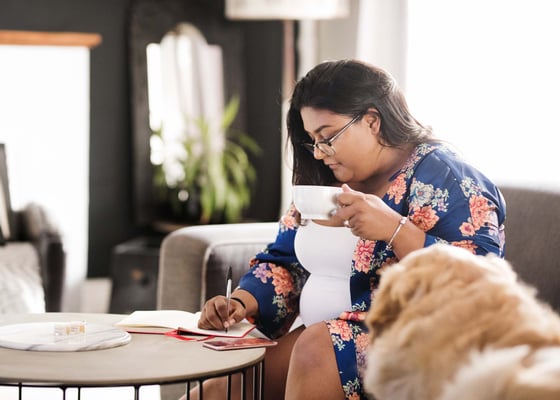 woman drafts a listicle in a notebook on a couch