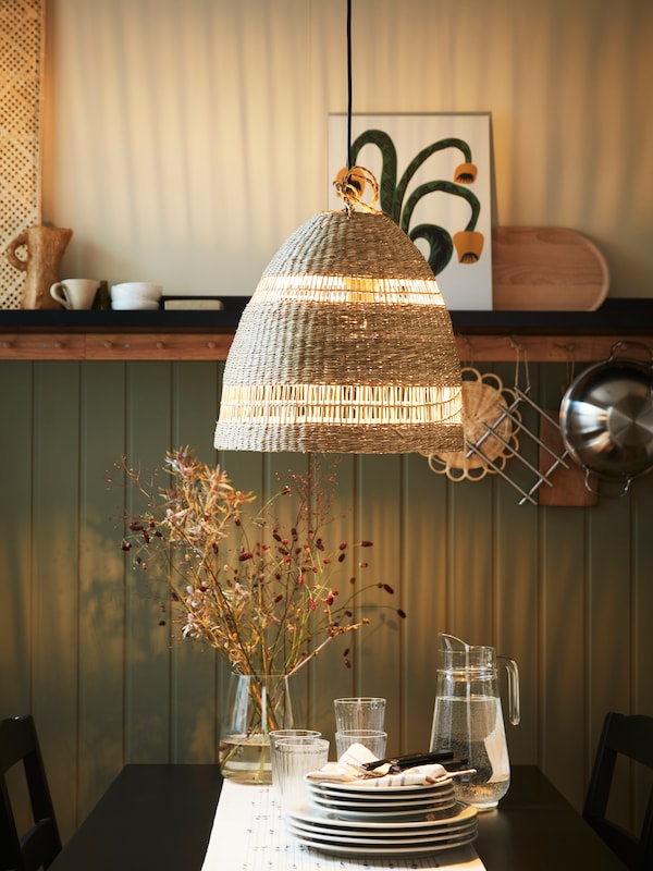 A TORARED pendant lamp shade hangs above a HÄGERNÄS table with a TILLBRINGARE jug and other items on it.