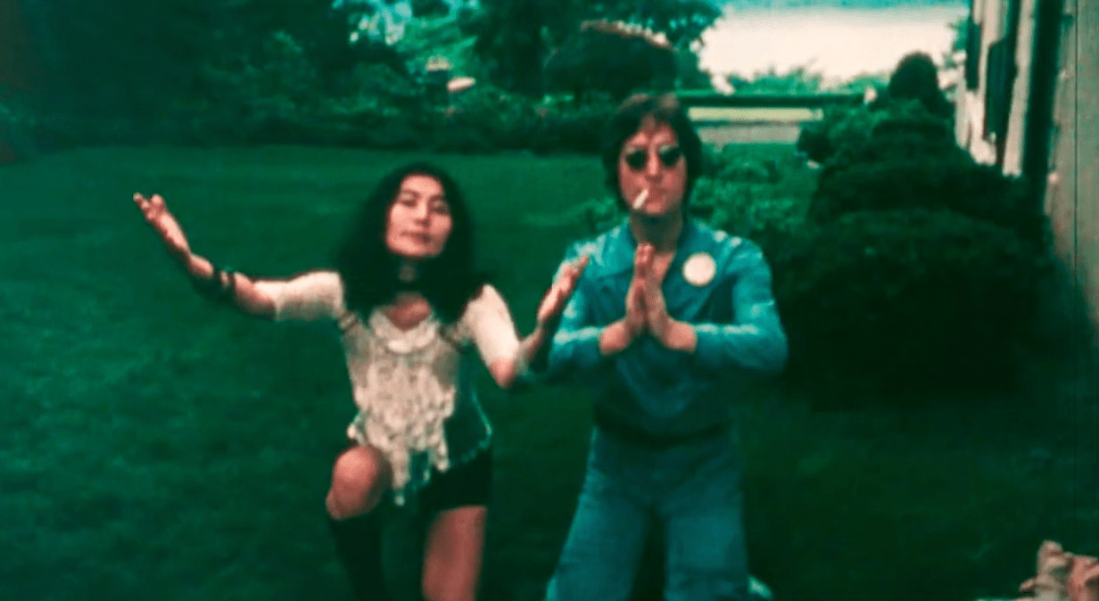 archival photo of Yoko Ono and John Lennon outside with arms outstretched