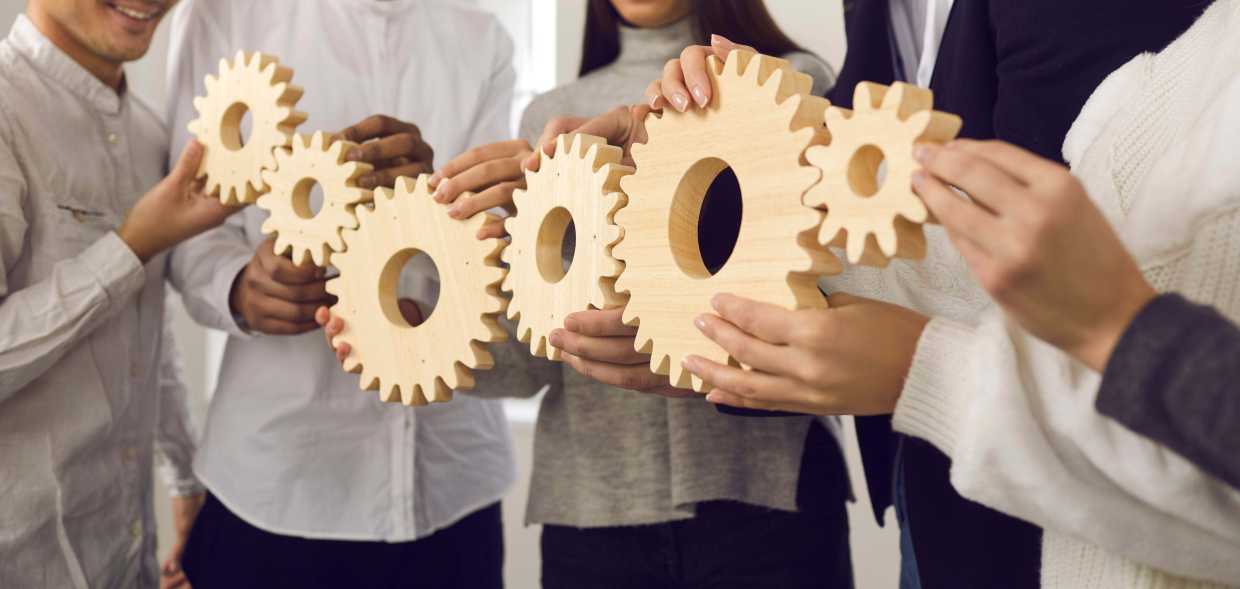 shutterstock 1869308242 team putting together a chain of gears teamwork coordination collaboration