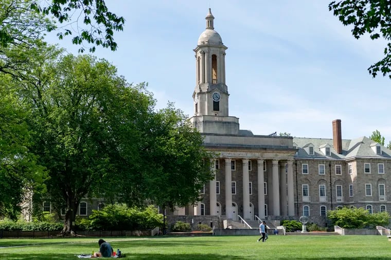 People stroll across Old Main lawn on the Penn State campus in this May 2021 photograph.