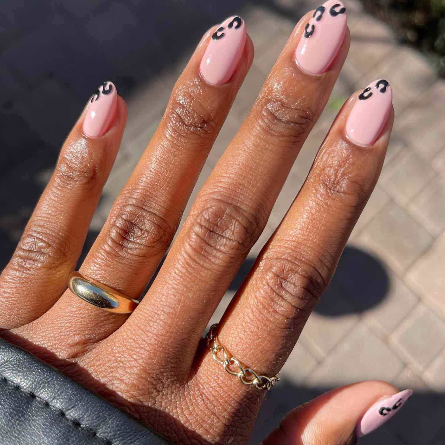 close up of nails with light pink manicure with black leopard print on tips