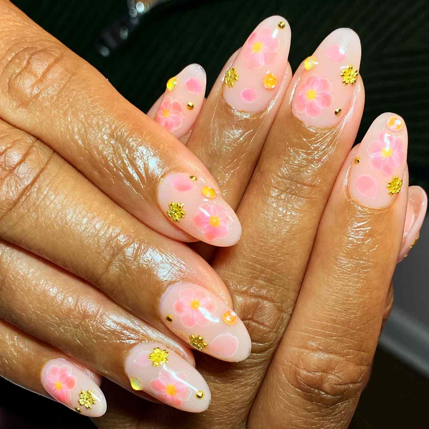 close up of nails with light pink manicure with pink and gold flowers