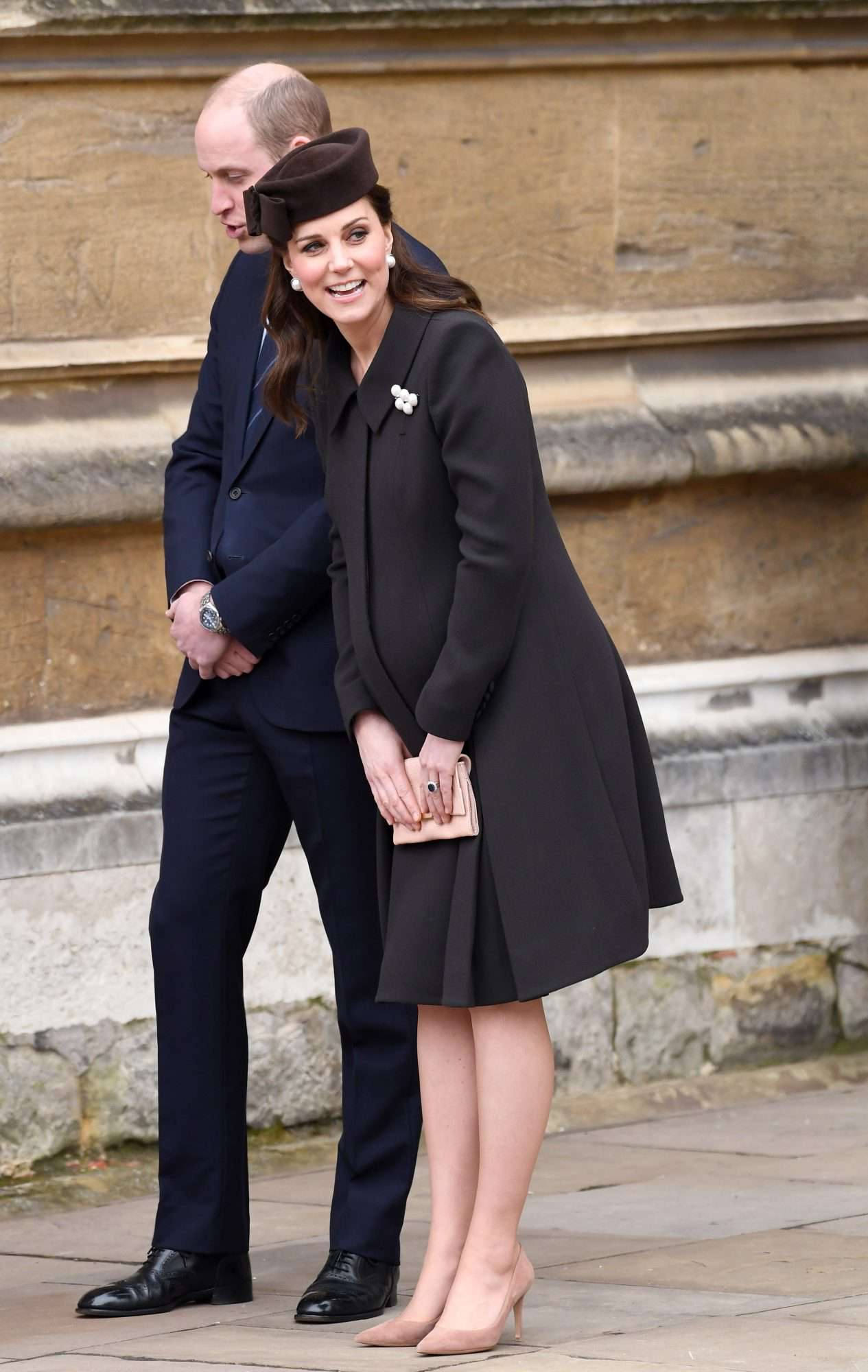 Kate Middleton in a dark brown coat and pillbox hat with nude pumps