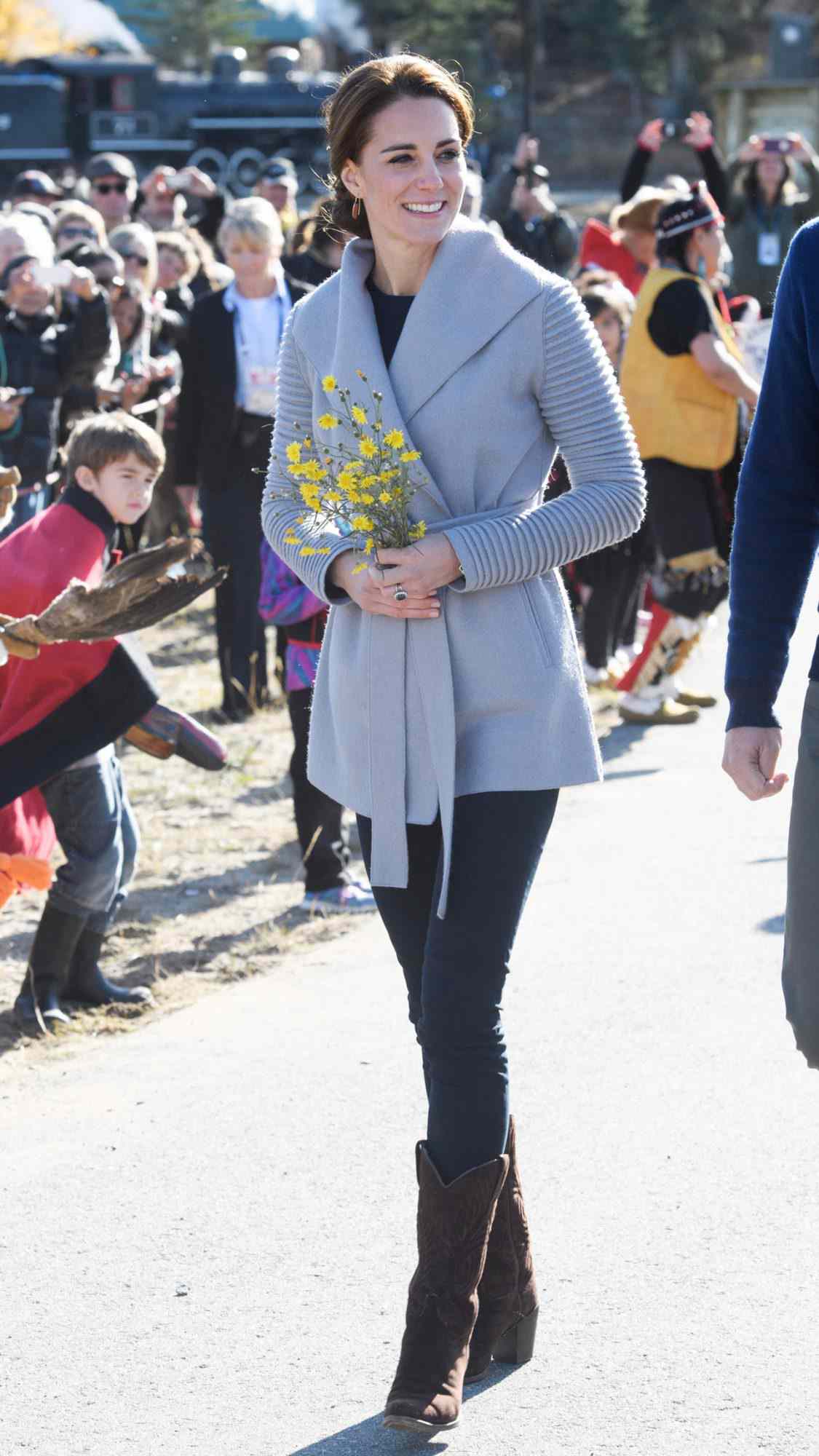 Kate Middleton in a gray Sentaler alpaca wrap coat with the Canadian brand's signature ribbed sleeves, dark skinny jeans, and brown cowboy boots