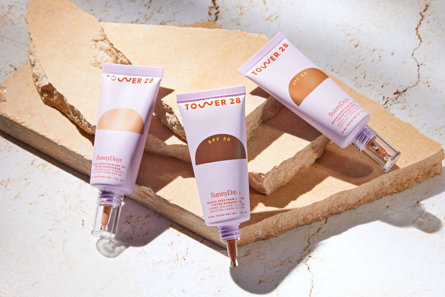 An assortment of Tower 28 SunnyDays SPF 30 Tinted Sunscreen displayed on marble countertop