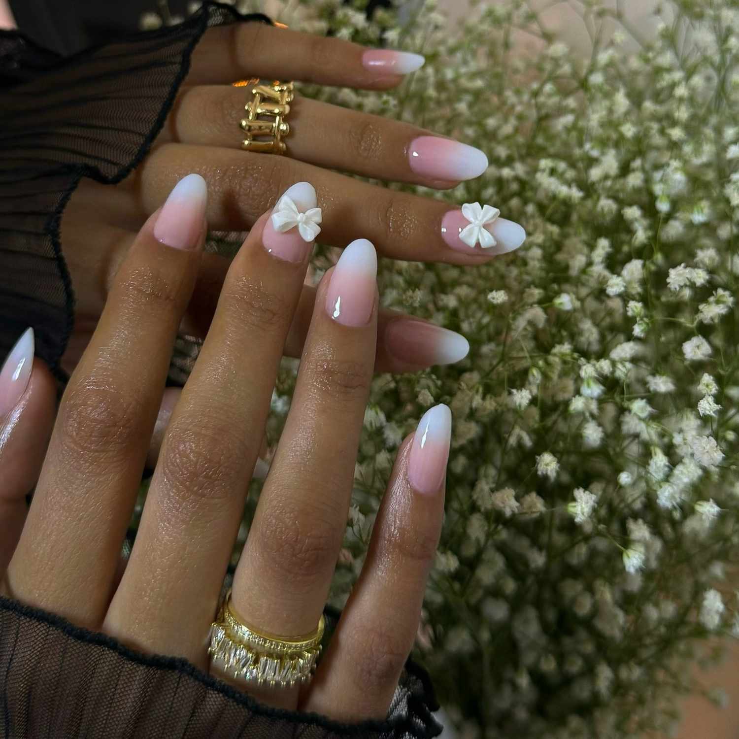 close up of nails with light pink and white ombre manicure with 3d bows on two nails