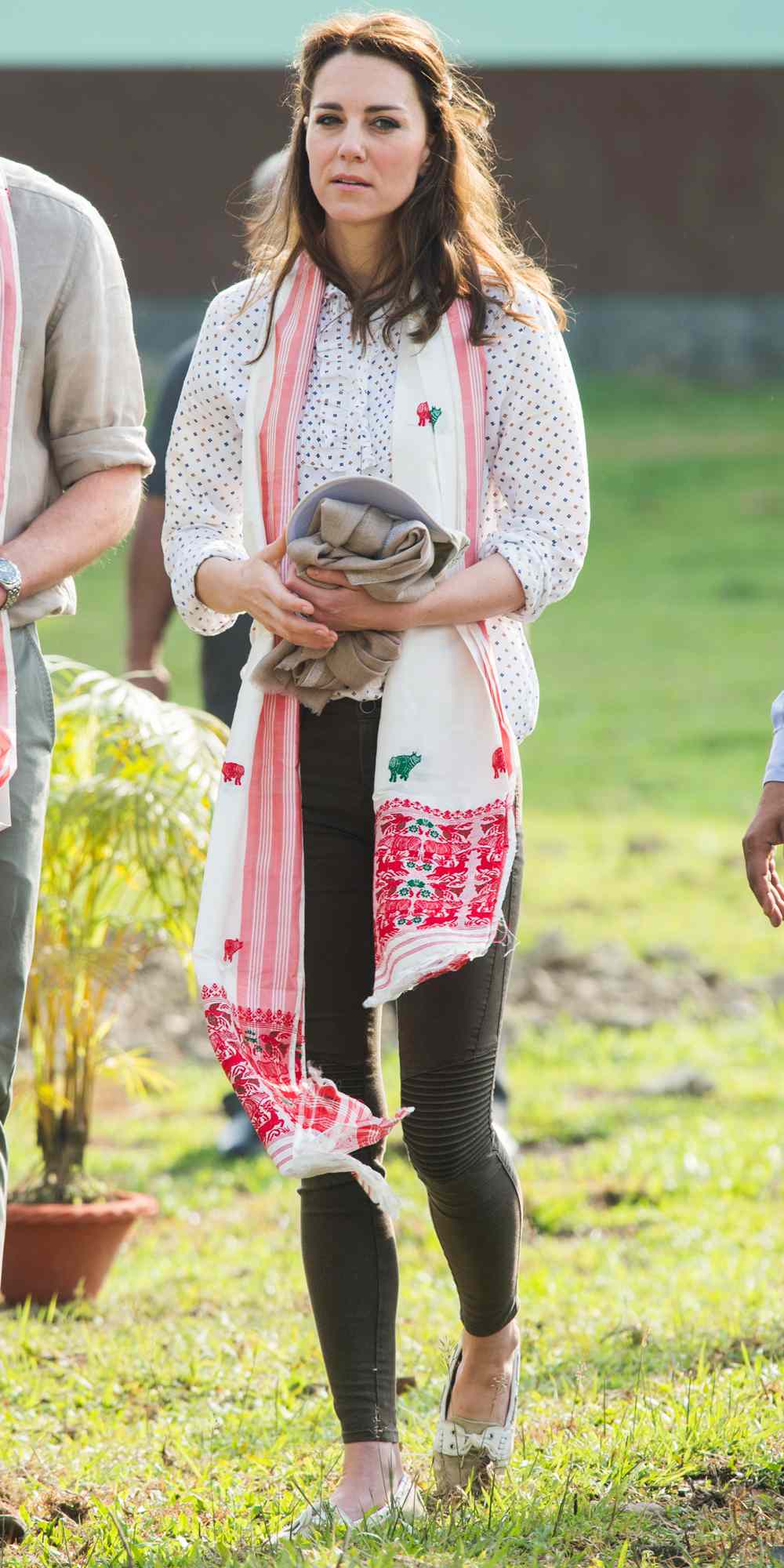 Kate Middleton in a polka-dot blouse, patterned scarf, and dark pants