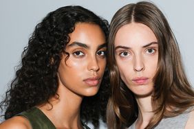 Two models pose backstage at a fashion show.