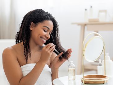 Woman applying rosemary oil for hair growth on the ends of her hair.