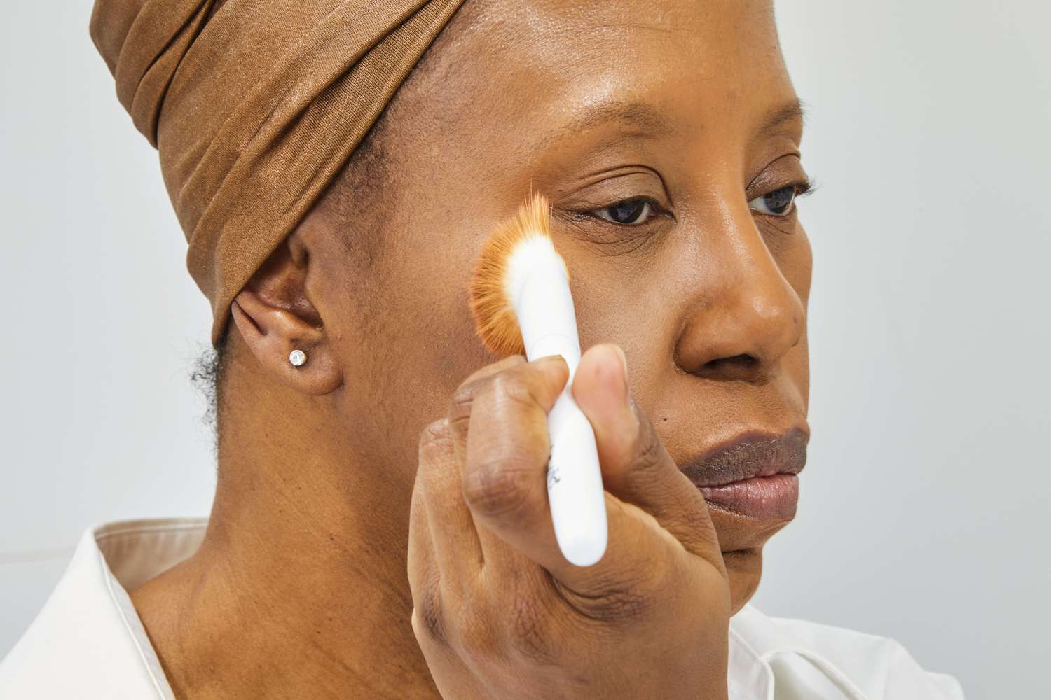 Person applying makeup to their face using a brush