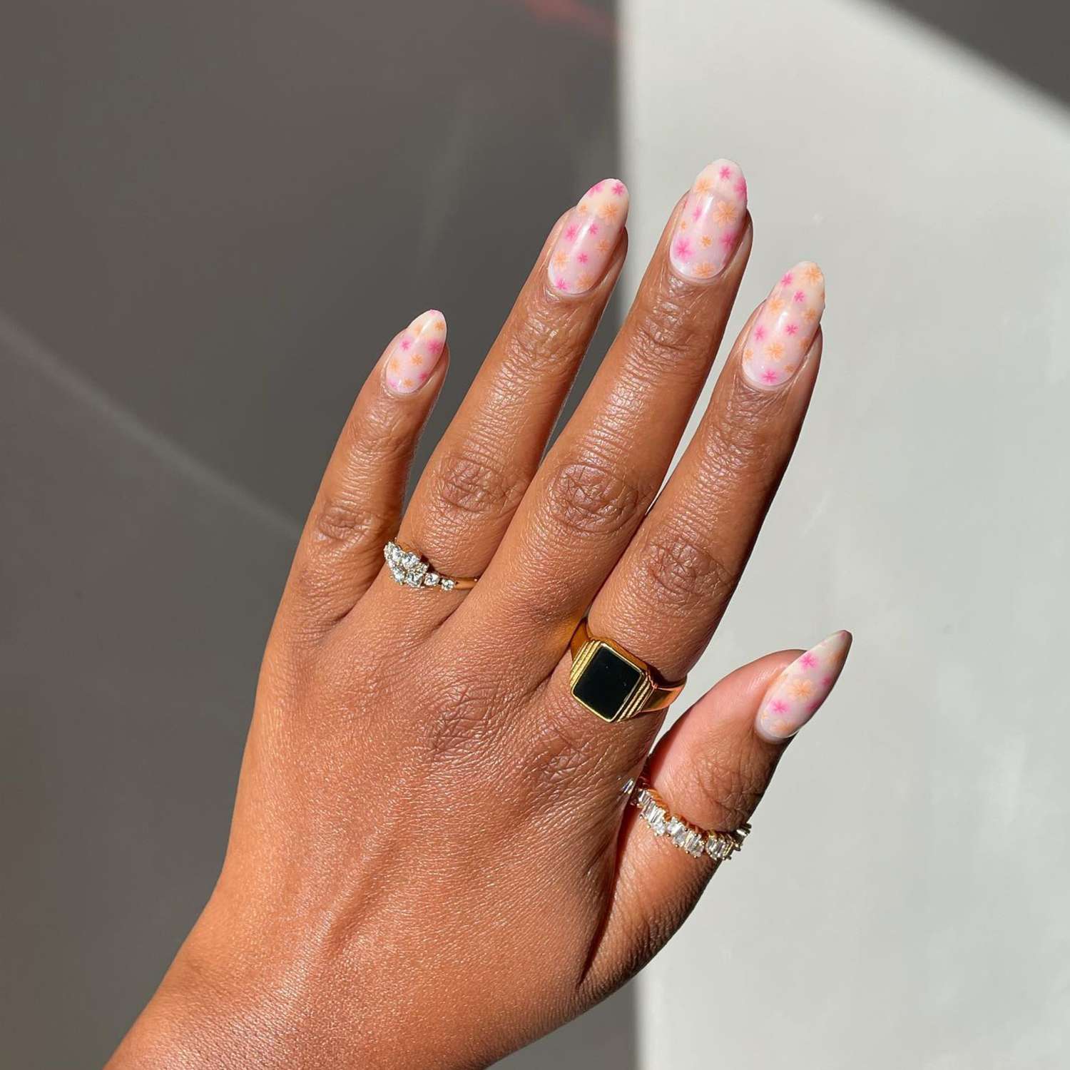 close up of nails with light pink manicure with pink and orange flowers