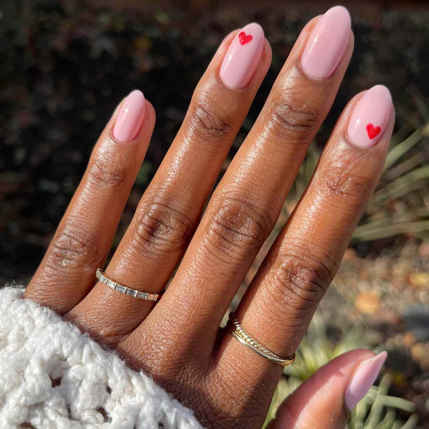 close up of nails with light pink manicure with red hand painted hearts