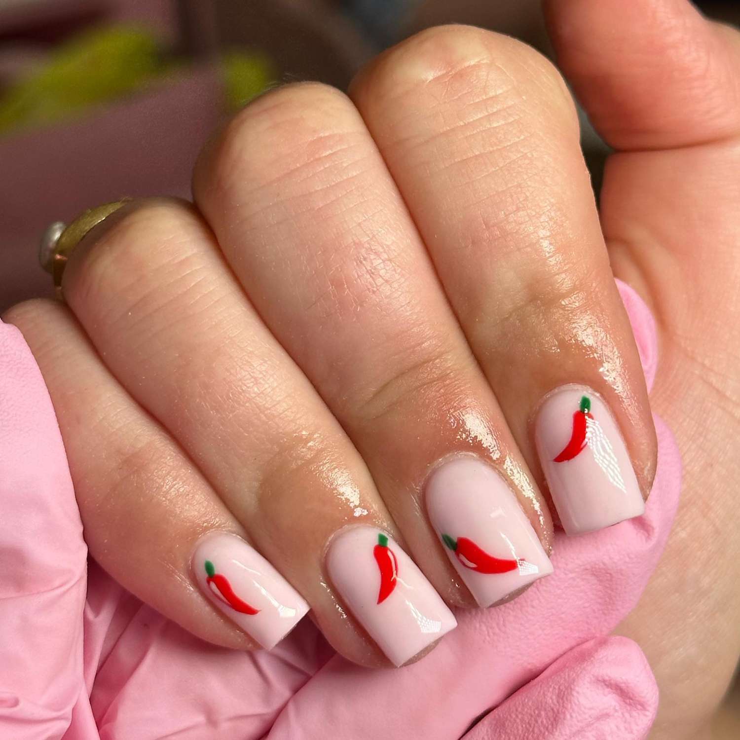 close up of nails with light pink manicure with chili pepper designs on each nail