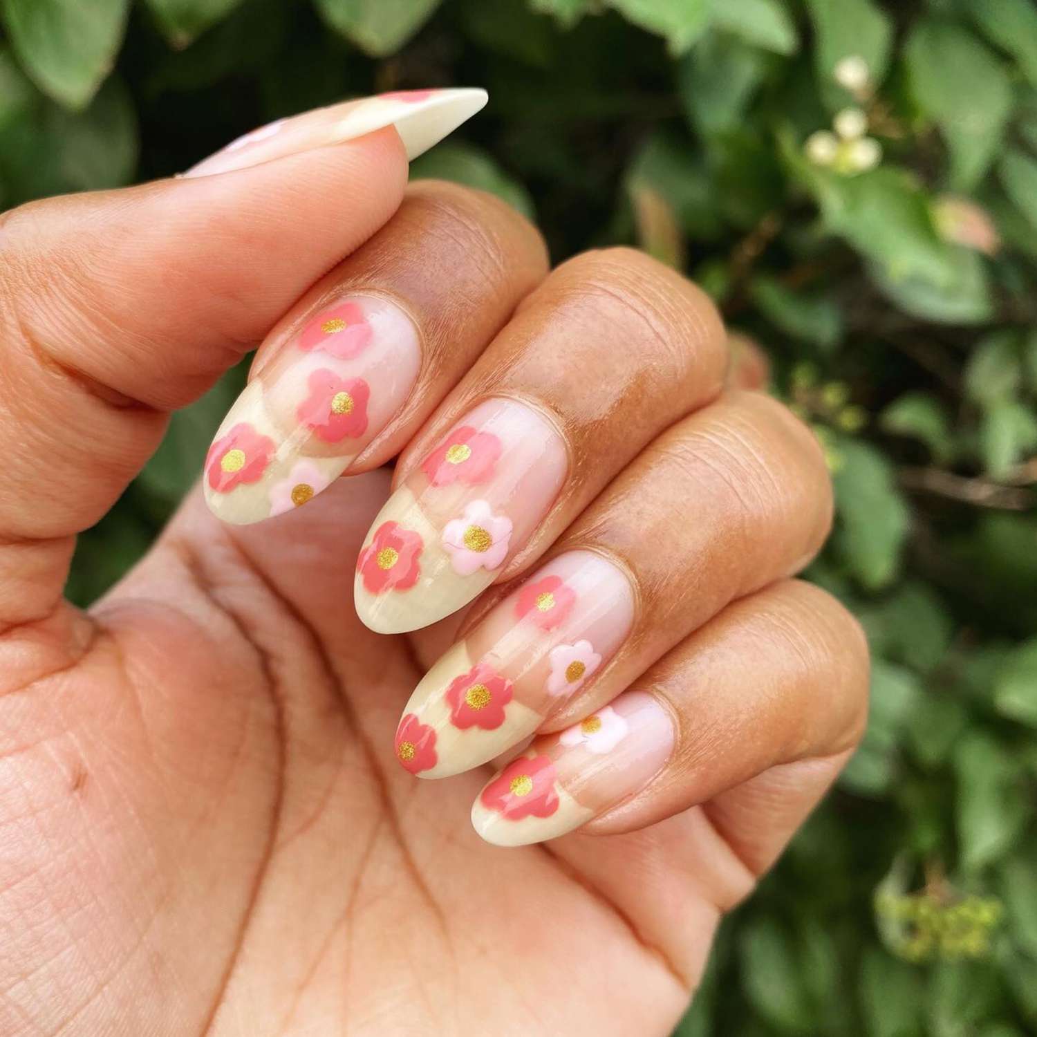 close up of nails with light pink manicure and yellow french tips with pink hand painted flowers