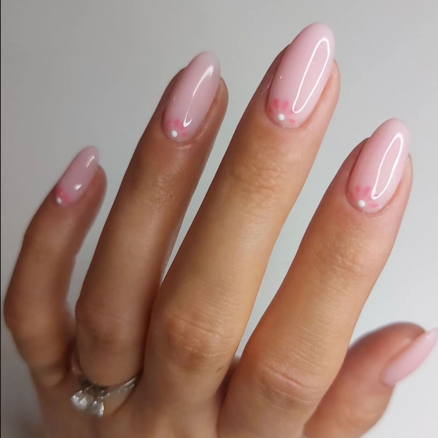 close up of nails with light pink manicure with floral design close to nail bed