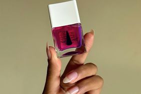 Hand with long nail manicure holding nail polish bottle