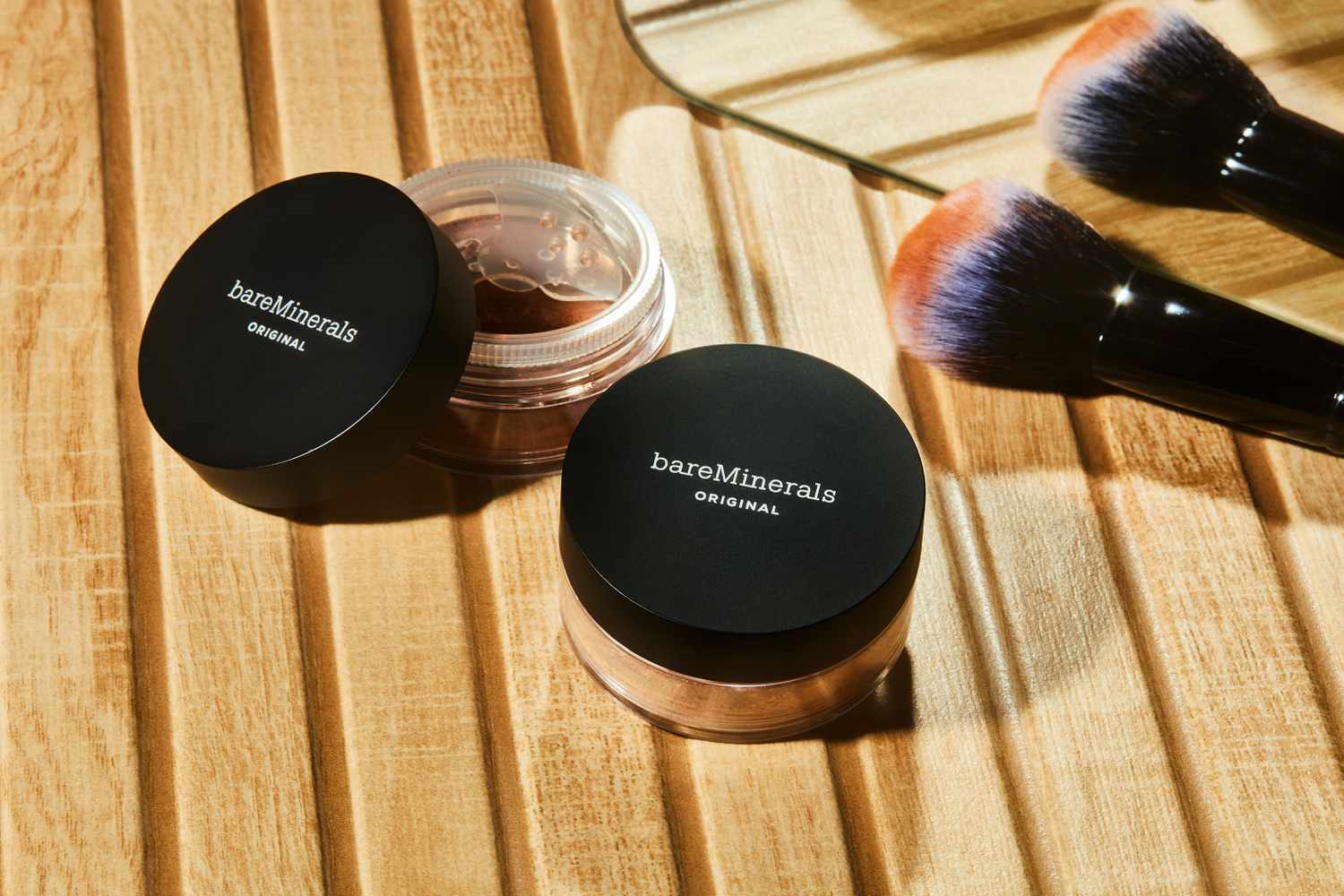 Two jars of bareMinerals Original Loose Powder Mineral Foundation SPF 15 with two brushes on wood surface