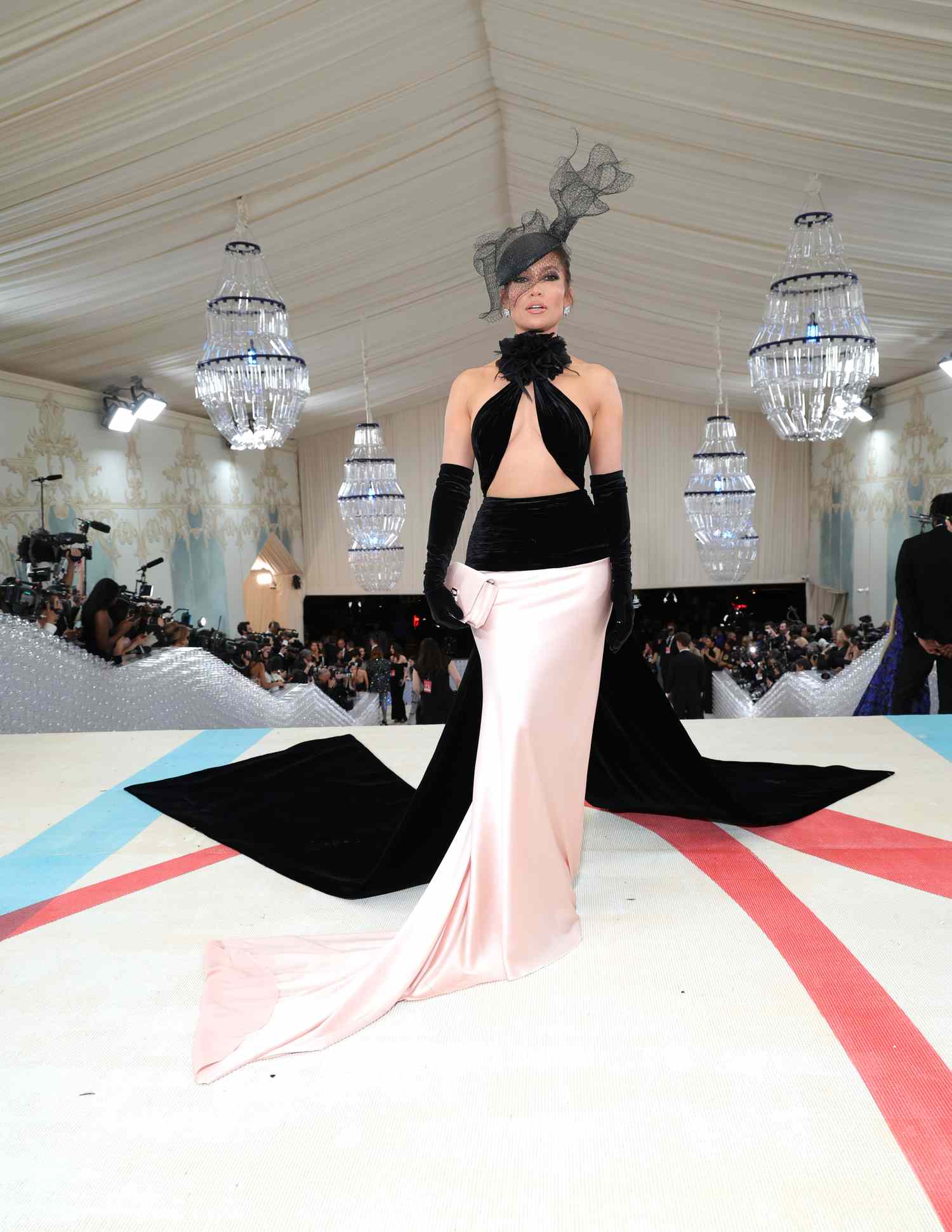 Jennifer Lopez poses for a photo in a black and pink gown with a black hat and black gloves