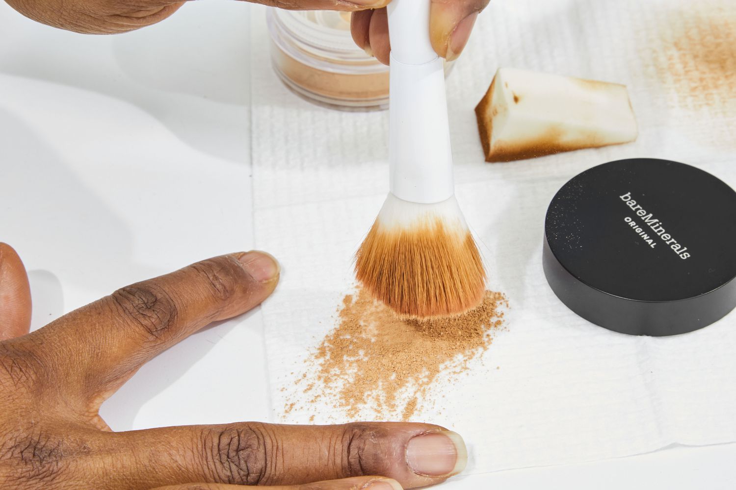 Hands holding a brush with bareMinerals Original Loose Powder Mineral Foundation SPF 15 