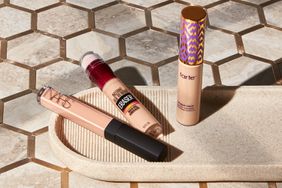 Assortment of the best under-eye concealers we recommend on a tan dish
