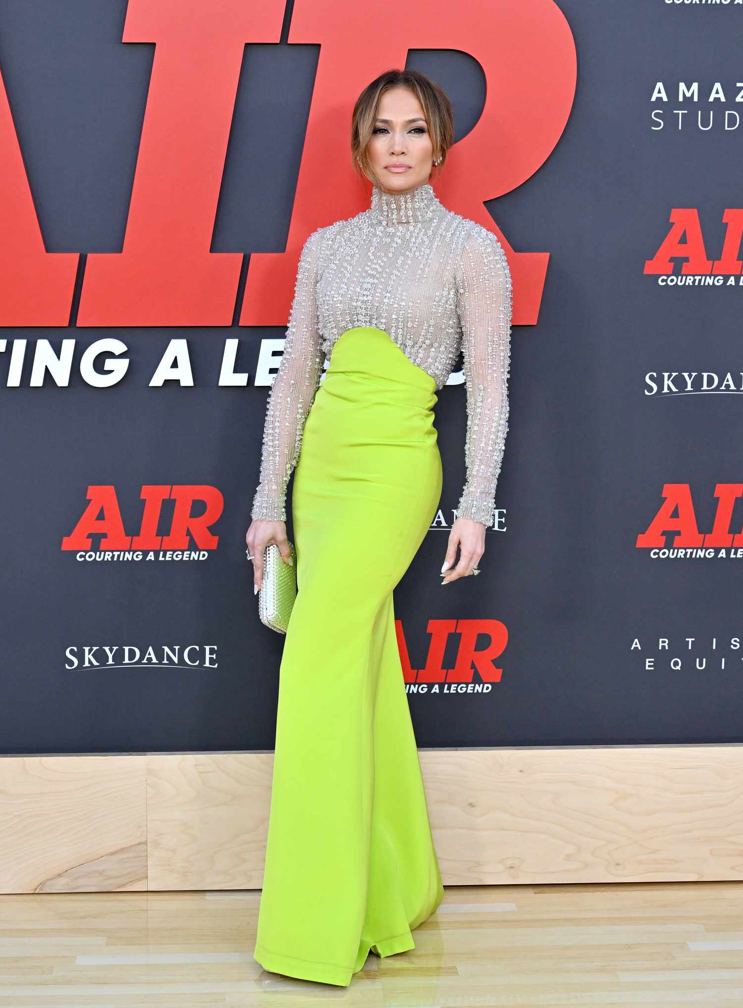 Jennifer Lopez poses for a photo in a silver and neon green gown