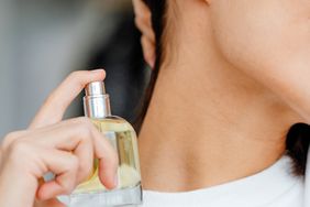 A woman spraying perfume on her neck.