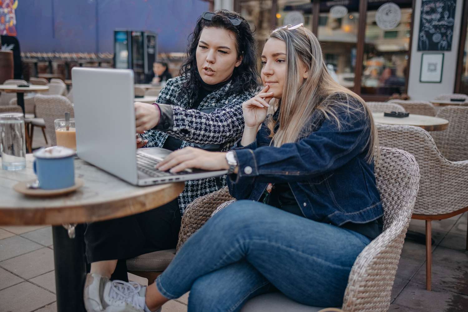 Two people sitting inside a cafe discussing opening a cash management account.