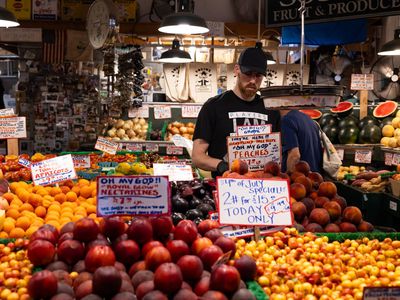  worker arranges peaches at a fruit stand in the Pike Place Market in Seattle, Washington, US, on Thursday, July 4, 2024.