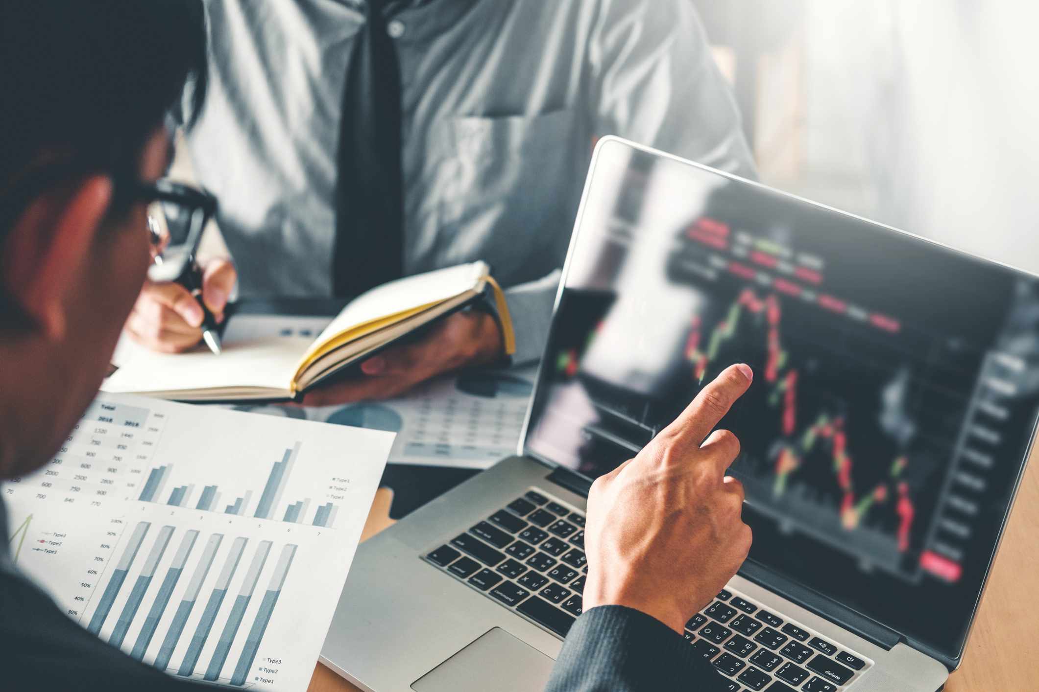 A man works at a laptop and reviews stock charts from an online broker.