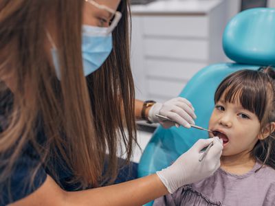 A female dentist examines a little girl's teeth