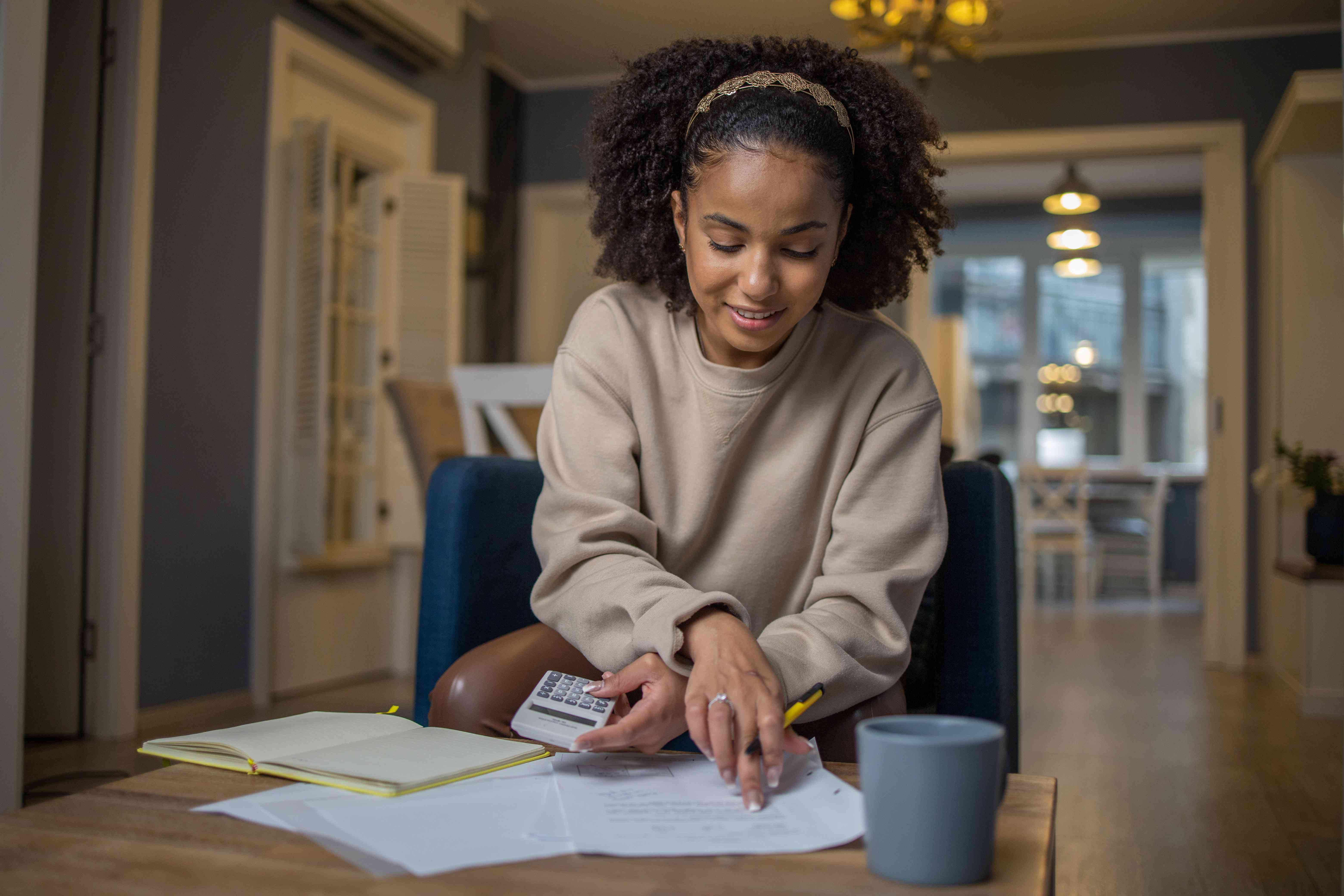 Young woman looking at a document and holding a calculator