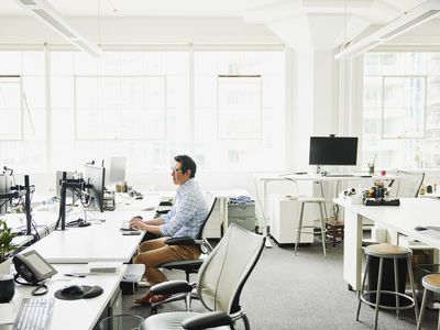 Wide shot of businessman working on computer at workstation in empty office