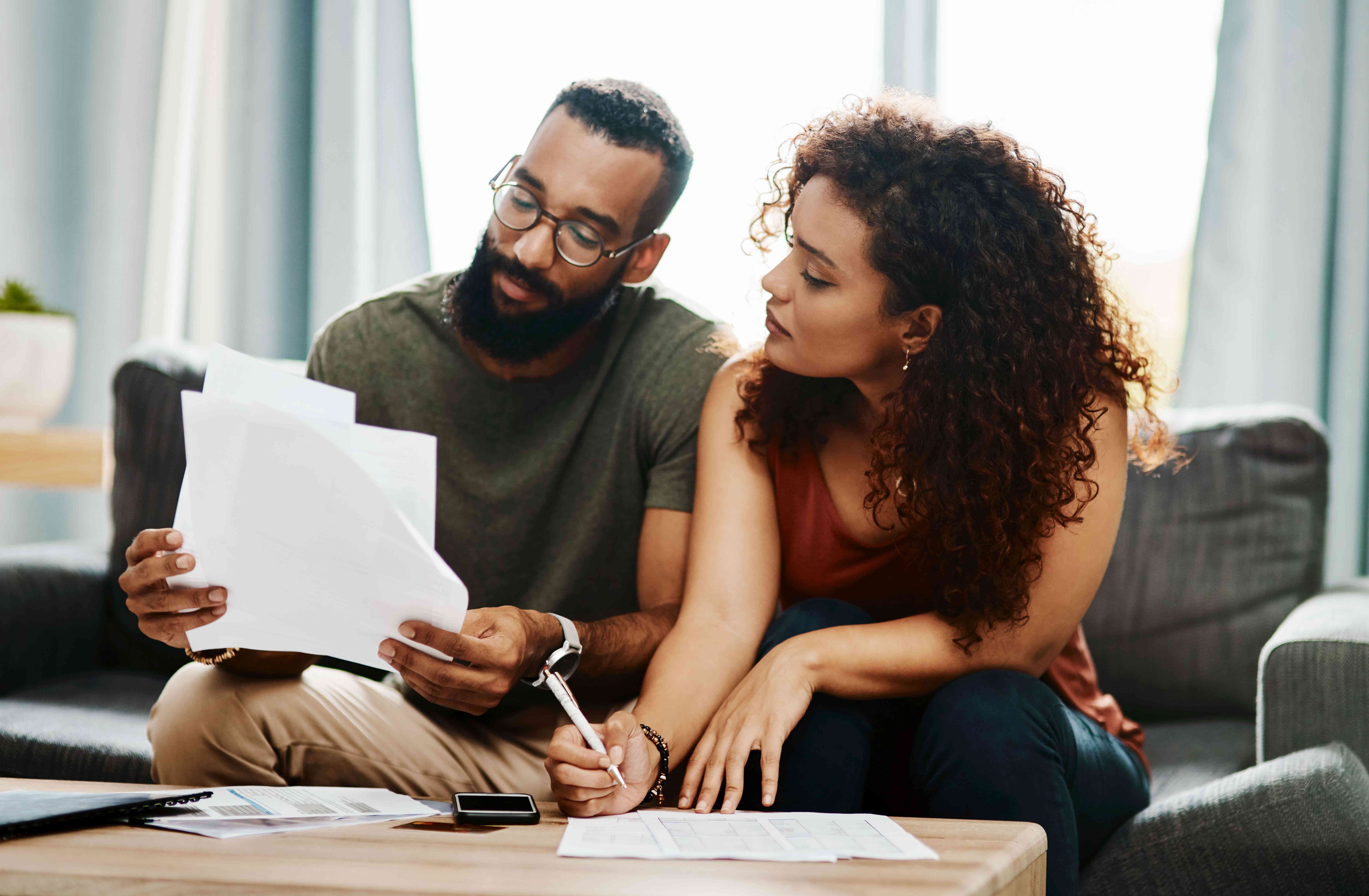 Two people discussing paperwork on a couch at home