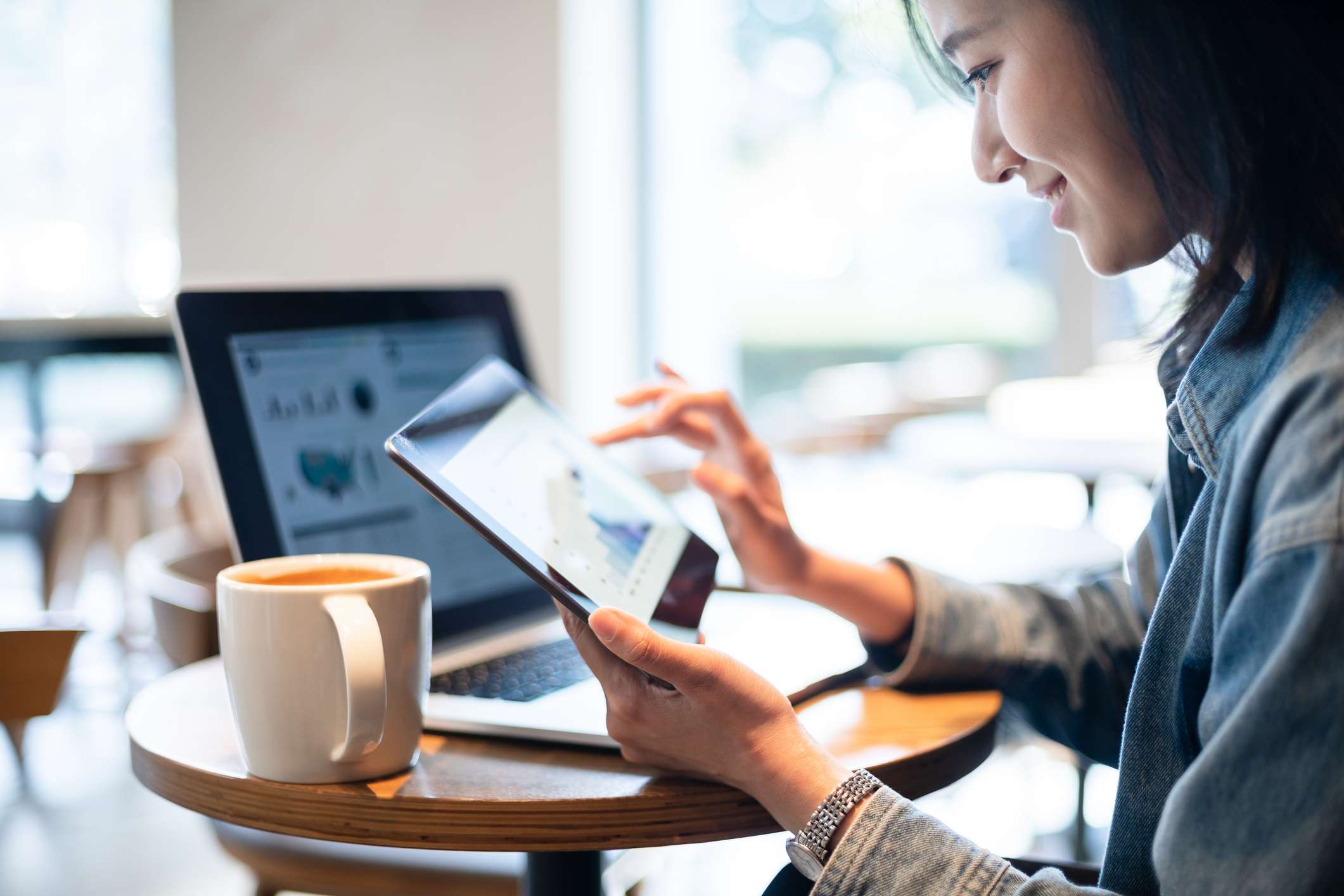 A young investor reviews investments on a laptop and tablet