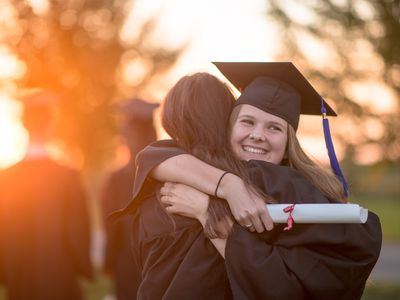 A college graduate hugs someone.