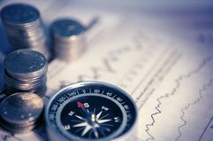 Stacks of coins, a compass and documents signaling finances