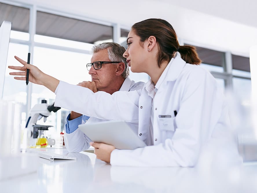 Woman and man mentor in medical research working together on pc with scientific student.